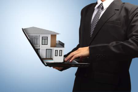 Real Estate Agent holding a laptop with a home 