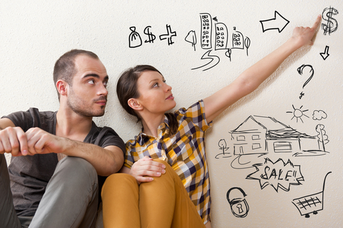 man and woman sitting against a wall pointing to drawing on the wall of house buying images
